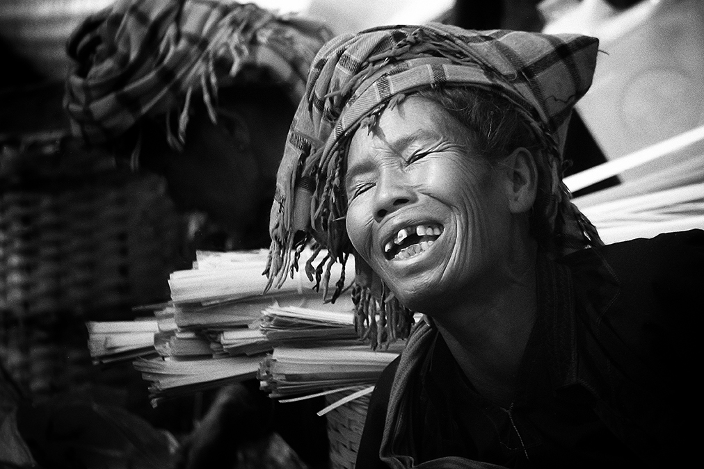 Photograph of a lady in Myanmar laughing while dealing with a customer